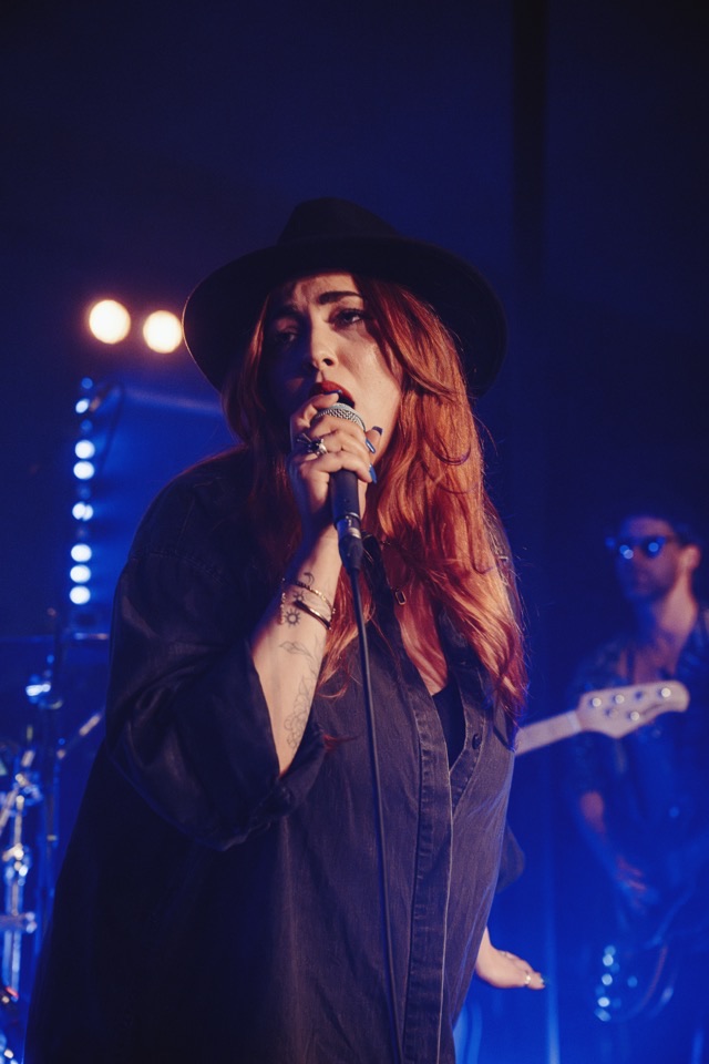 A lead vocalist mid-song under blue stage lighting